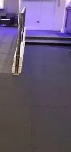 Smooth black flooring leads to a stairway with a handrail
