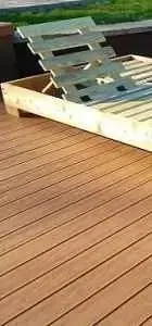 wooden deck featuring smooth planks, with a lounger positioned at the edge